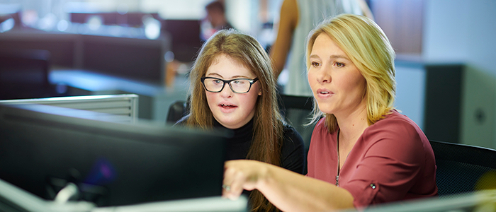 Female student and female teacher sitting in front of computer